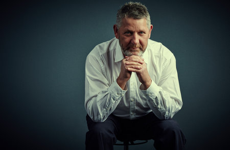 Its important to make the right business decisions. Studio portrait of a handsome mature businessman looking thoughtful while sitting down against a dark background.の写真素材