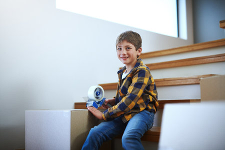 He didnt know packing would be so much fun. an adorable little boy packing boxes on moving day.の写真素材