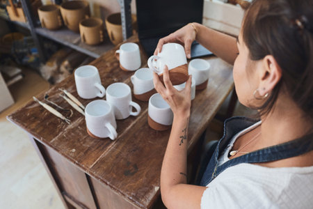 No scratch means its up to scratch. a young woman making mugs in a pottery studio.