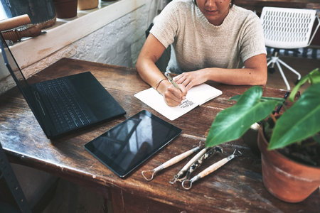 Jotting down all my tasks for the day. an unrecognizable business owner sitting alone in her pottery...