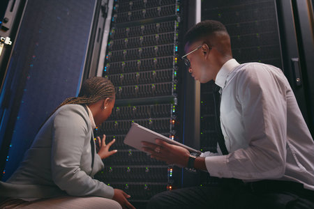 We might need to seek extra help. two young IT specialists crouched down in the server room together...