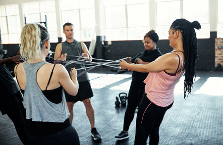 You can achieve so much more together. a fitness group working out with resistance bands in their...
