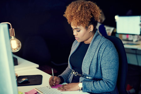 Its a late night work session. a young businesswoman working late in an office.の写真素材