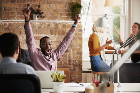Wow, success and black man in happy celebration at work after sales, goals or reaching target in an office. Job promotion, winner or excited employee with arms in the air to celebrate winning a dealの写真素材