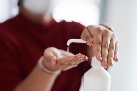 Taking precautions to ensure her health at work. Closeup shot of an unrecognisable businesswoman using hand sanitiser in an office.の写真素材