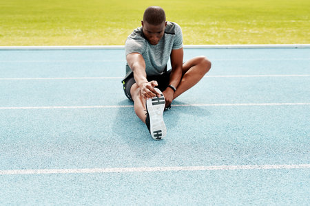 Athlete man, sitting and track for stretching legs to start training, exercise or running for...