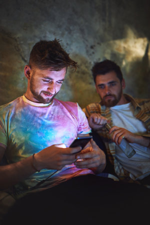 Okay I found the video. two handsome young man using a smartphone while sitting with his friend at home.の写真素材
