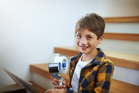 Im ready to help pack today. an adorable little boy packing boxes on moving day.の写真素材