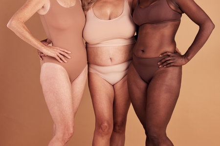 Diversity, closeup or women with body positivity, wellness or support on brown studio background. Multiracial, females or ladies with solidarity, skincare or confident for natural beauty or communityの写真素材