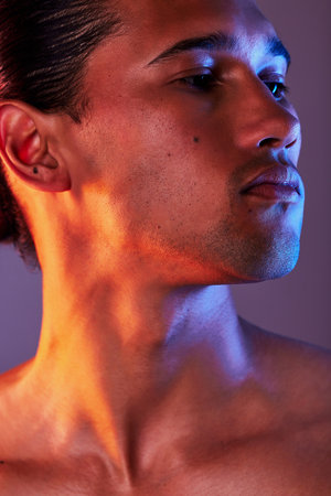Beauty, neon and face of man in studio for skincare, self care and facial treatment on purple background. Creative aesthetic, glow and profile of male model for healthy skin, wellness and confidenceの写真素材