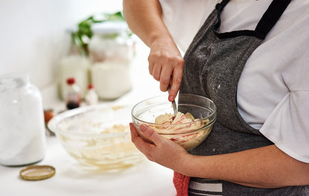 Now for the decoration...an unrecognizable woman mixing icing in a glass bowl.の写真素材