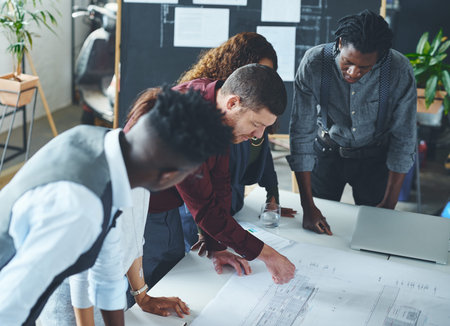 Lets make this our best work. a team of professionals working on blueprints in an office.