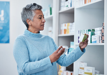 Senior woman, pharmacy and choice with box, medicine and decision with shopping for healthcare. Elderly customer, retail drugs and pharmaceutical pills for health, wellness and medical store by shelfの写真素材