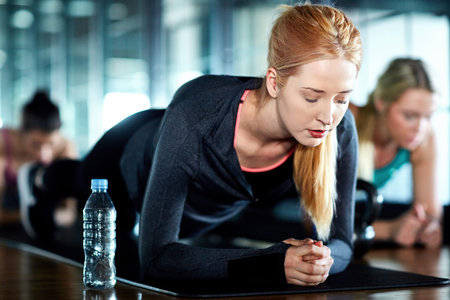 Core strength. an attractive young woman planking as part of her workout in the gym.