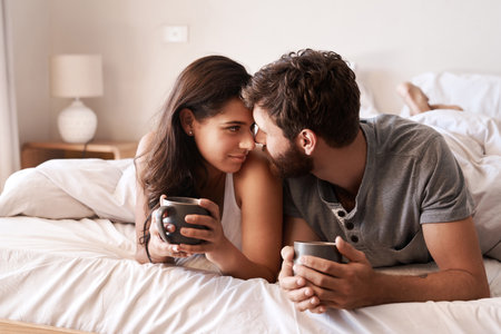 Home bedroom, coffee and couple bonding, relax and enjoy morning latte, espresso or beverage drinks. Forehead, marriage or romantic man, woman or people with tea cup, love and affection in hotel bedの写真素材