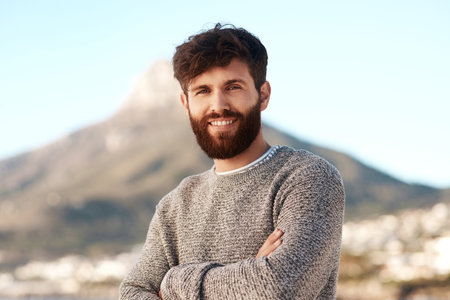 Nature portrait, arms crossed and happy man relax with outdoor wellness, vacation freedom and smile for peace. Summer sunshine, mountain and male person on travel holiday in Cape Town, South Africaの写真素材