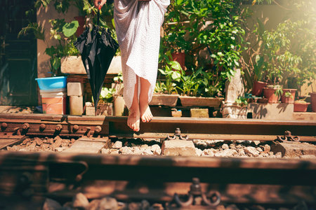 Feet were made for exploring. a woman walking barefoot on train tracks through the streets of Vietnam.の写真素材