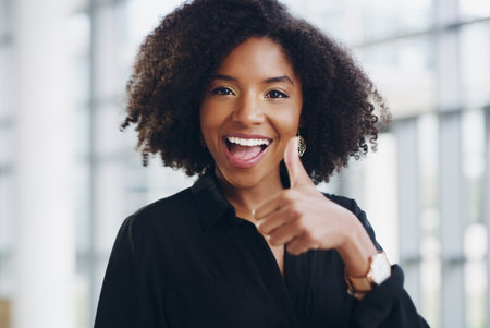Black woman in business, face and thumbs up with smile, support and agreement, thank you and success at job. Emoji, hand gesture and excited female professional in portrait with positive feedbackの写真素材