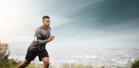 Man, running and space for fitness with cityscape for exercise, wellness or music with mockup for health. African male runner listening to audio for focus, workout and nature outdoor with mock up skyの写真素材