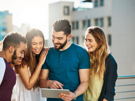Technology can be enjoyed together. Shot of young friends using a tablet outside.の写真素材
