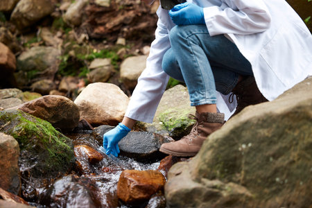 Science, river and woman with test tube for water for environment inspection, check and sample. Sustainability, agriculture and hands of female scientist in forest for analysis, research and studyの写真素材