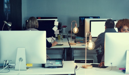 In this office, success never sleeps. a group of businesspeople working late in an office.の写真素材