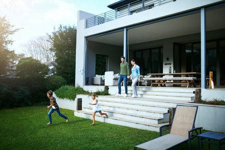 Excited to be playing outside. a young family in the backyard at home.の写真素材