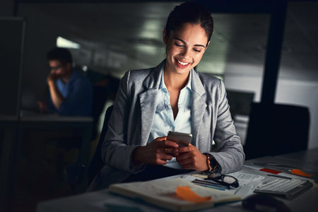 Success will come to those who work for it. Shot of a young attractive businesswoman working late at night in a modern office.の写真素材