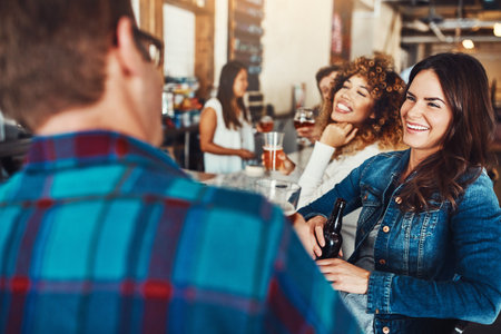 Hanging with the ladies. a young couple enjoying a drink at a bar.の写真素材