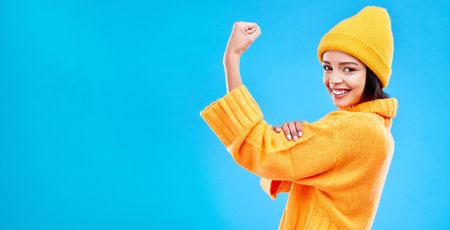 Strong, mockup and a portrait of a woman with muscle isolated on a blue background in a studio. Smile, style and a girl showing fashion for empowerment and confidence on a backdrop with spaceの写真素材