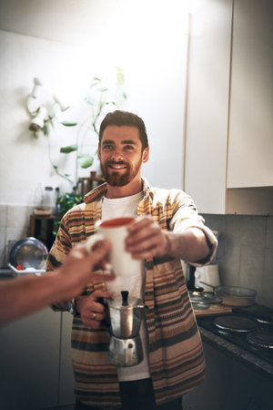 Why thank you friend. POV shot of an unrecognizable man receiving a cup of coffee inside of the kitchen during the day.の写真素材