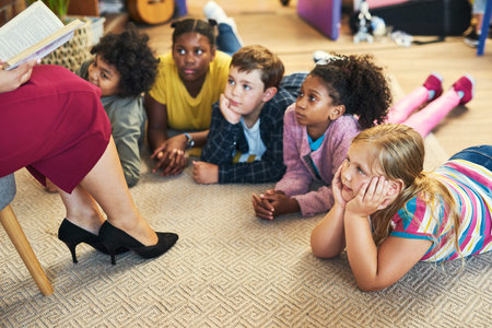 We love a good story. a diverse group of children lying on their classroom floor and listening to...