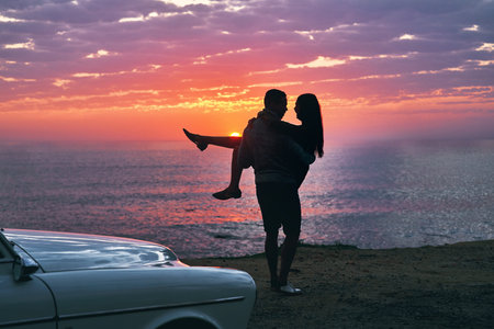 He knows how to sweep me off my feet. a young couple making a stop at the beach while out on a road...