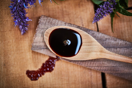 Theres a lot to love about lavender. a wooden spoon with dark liquid in it surrounded by fresh lavender on a table.の写真素材
