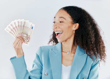 Winner, finance and cash with a business woman in studio on a gray background looking surprised or happy. Economy, wealth and money with a female employee holding euro bills for investmentの写真素材