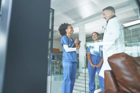 Smiles are contagious, spread them to the patients. an attractive young nurse standing with coworkers and having a discussion in the clinic.の写真素材
