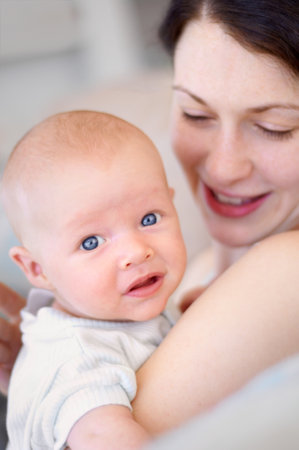 Happy, care and portrait of a mother with a baby for bonding, love and happiness. Smile, caring and a mom holding and embracing a newborn child for childcare, motherhood and parenting in a houseの写真素材