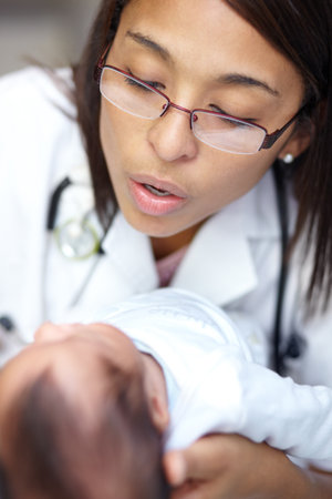 Healthcare, medicine and a pediatrician with a baby in the hospital for insurance, care or treatment. Medical, kids and a doctor woman holding a newborn infant in a health clinic for an appointmentの写真素材