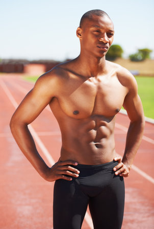 Body, mindset and topless man at a race track for training, fitness and sport, cardio and speed running practice. Stadium, start and African male runner serious, focus and ready for performance runの写真素材