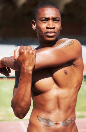 Body, stretching and man runner at a stadium for fitness, training and workout, warm up and focus. Start, stretch and African male athlete at a race track for cardio, exercise and sports performanceの写真素材