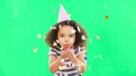 Little girl, birthday and blowing confetti on green screen for party celebration isolated against a studio background. Portrait of cute kid celebrating event with glitter decor for new year on mockupの写真素材
