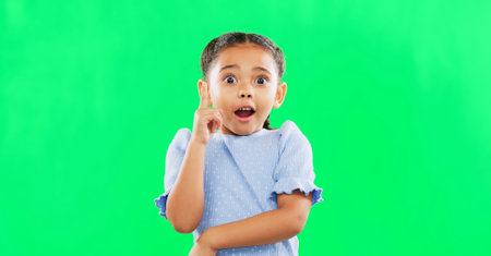 Face, green screen and child in studio with idea, answer or solution, happy and excited on mockup background. Portrait, wow and girl with surprised, emoji and lightbulb moment or eureka isolatedの写真素材