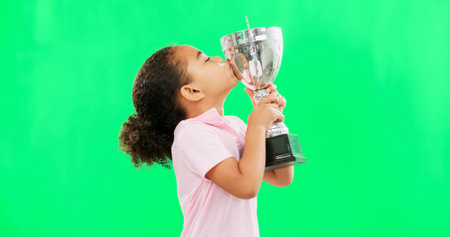 Celebration, win and face of child with trophy isolated on a green screen studio background....
