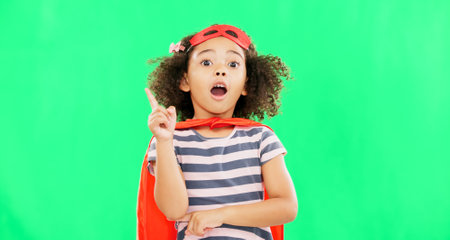 Thinking, superhero and child on green screen with idea stop crime and fight with fantasy or cosplay costume. Girl power, hero and pretend game with strong kid portrait to protect freedom and justiceの写真素材