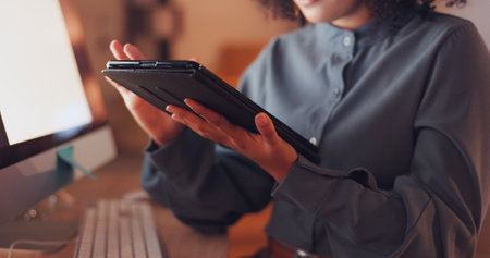 Technology, internet and information with employee browsing online for connection, website and deadline. Scrolling, tablet and hands of woman in office at night for research, overtime and analysis.の写真素材