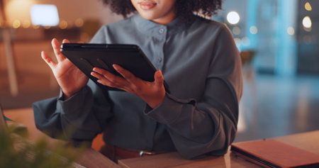 Scrolling, tablet and hands of woman in office at night for research, overtime and analysis. Technology, internet and information with employee browsing online for connection, website and deadlineの写真素材