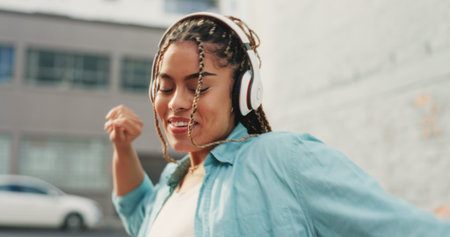 Woman, dancing and listening to music in the city with headphones for audio streaming in the...