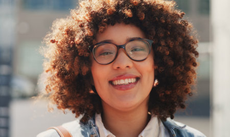 Business woman, happy and face of an employee walking in the city ready for work. Portrait, happiness and urban travel of a young person with a smile in the wind from success and walk in the sunの写真素材