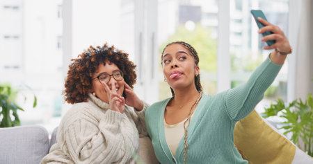 Woman, friends and smile for selfie, vlog or profile picture together with facial expression on living room sofa at home. Happy women smiling for photo, memory or funny social media post on couchの写真素材