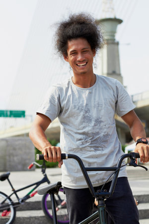 Portrait, bmx and man with bicycle in city, outdoor and training in street. Cycling, funny or person laugh with bike to travel in Brazil for sport, exercise or workout for fitness, health or wellnessの写真素材